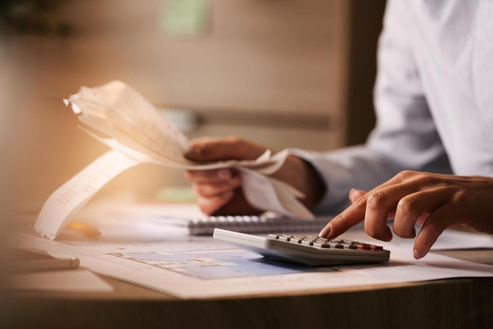 Personne utilisant une calculatrice pour la gestion comptable et administrative de l'entreprise.